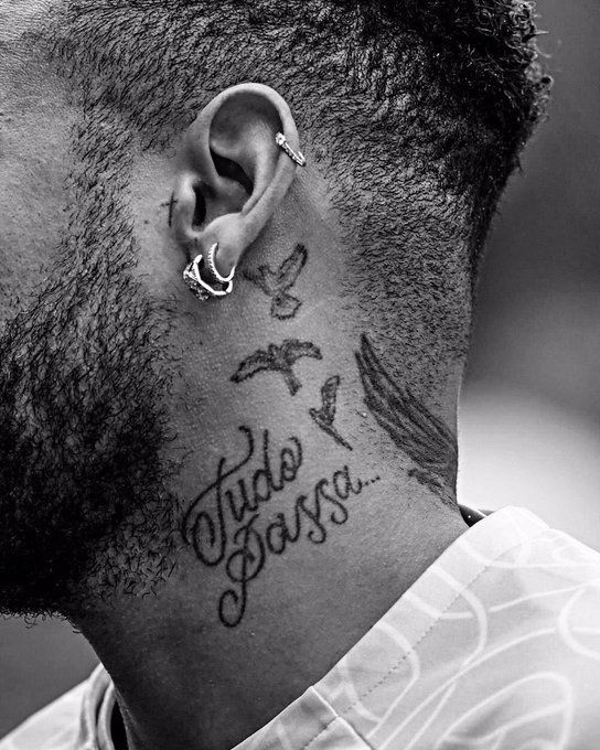 Black and white tattoo of birds and cursive script along the neck and hairline area, showcasing fine detail work near the hairline