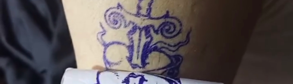 Fresh dagger tattoo stencil compared against the original paper design during a hygienic tattoo session in Lahore