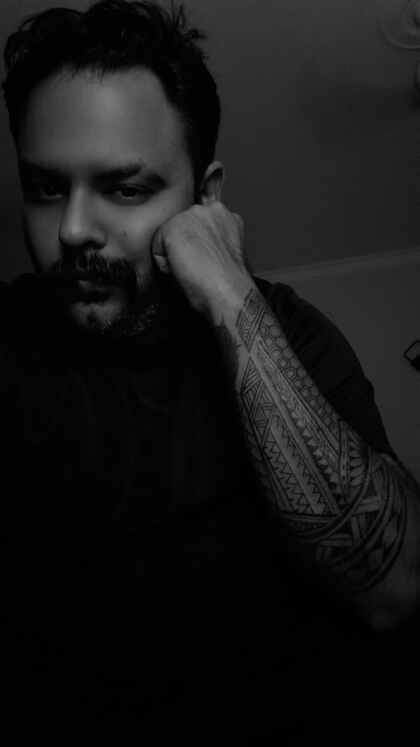 Lead tattoo artist at Devil Tattoo Lahore studio, DHA Phase 7 Y Block, black and white portrait showing Polynesian sleeve tattoo