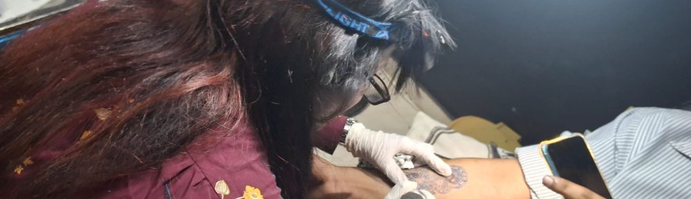 Female tattoo artist Monica tattooing a skull design on a client at Devil Art Studio Lahore