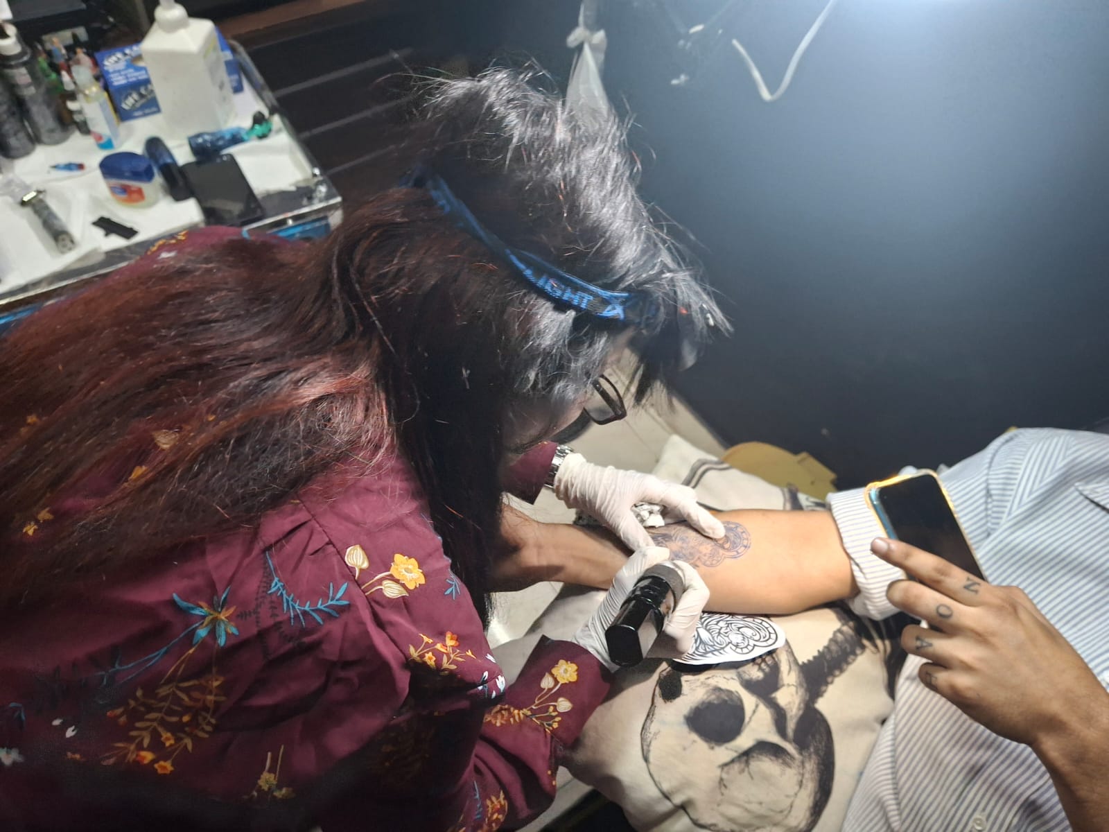 Female tattoo artist Monica tattooing a skull design on a client at Devil Art Studio Lahore