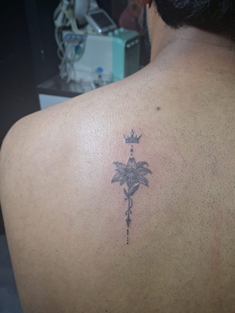 Minimalist fine line flower and crown back tattoo by Devil Art Studio Lahore